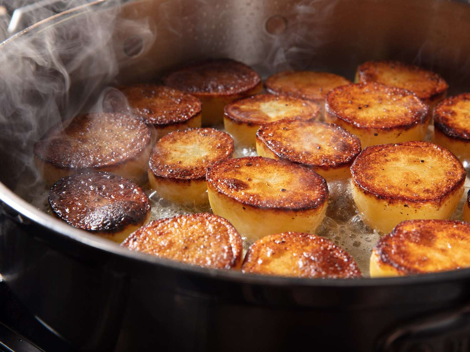 锅里的土豆一面烤焦，黄油冒着泡沫。