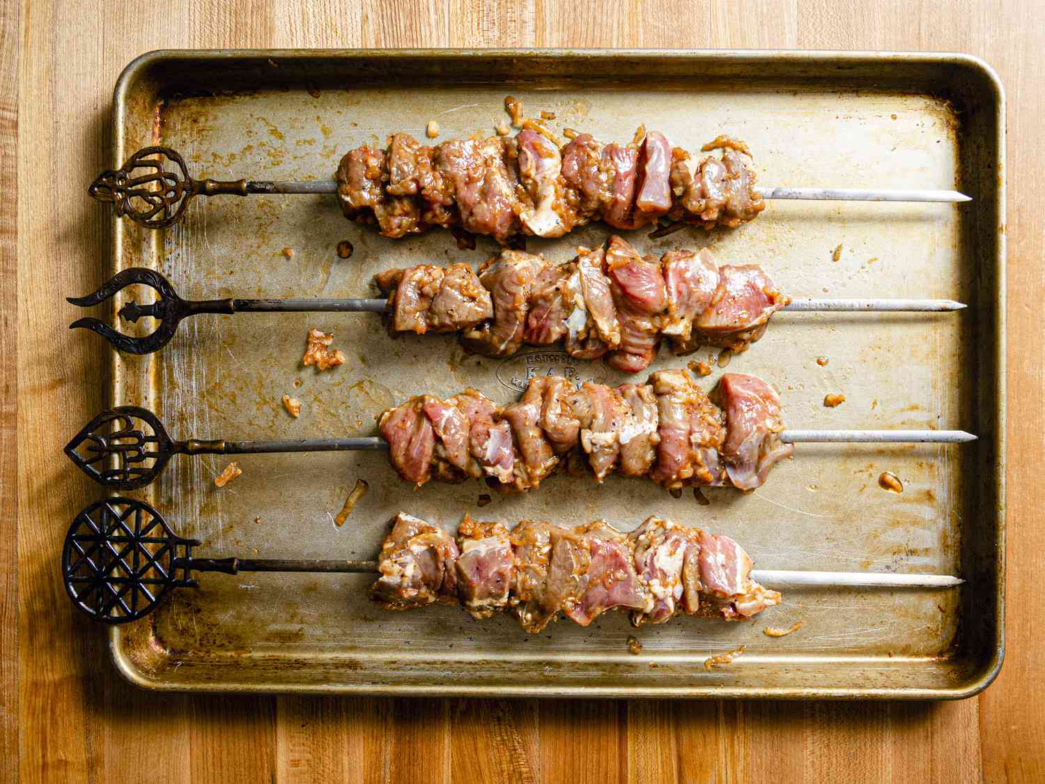 Overhead view of meat on skewers on a baking sheet