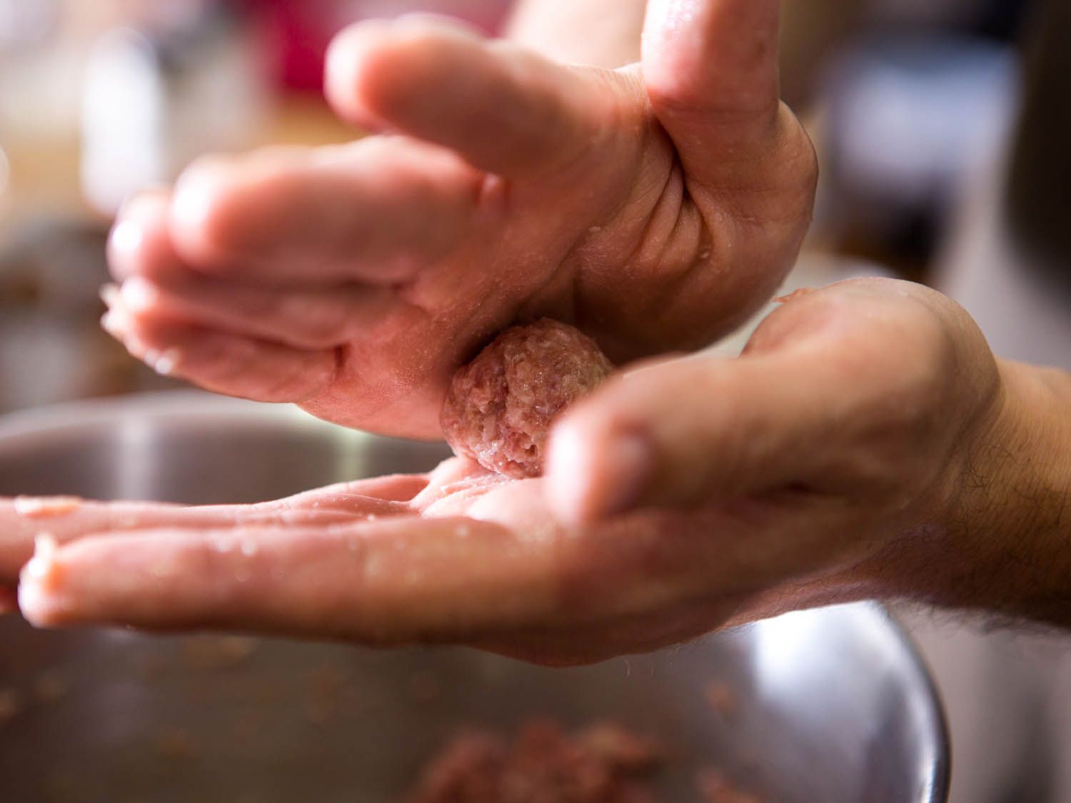 Rolling a raw meat mixture between palms to form a Swedish meatballs.