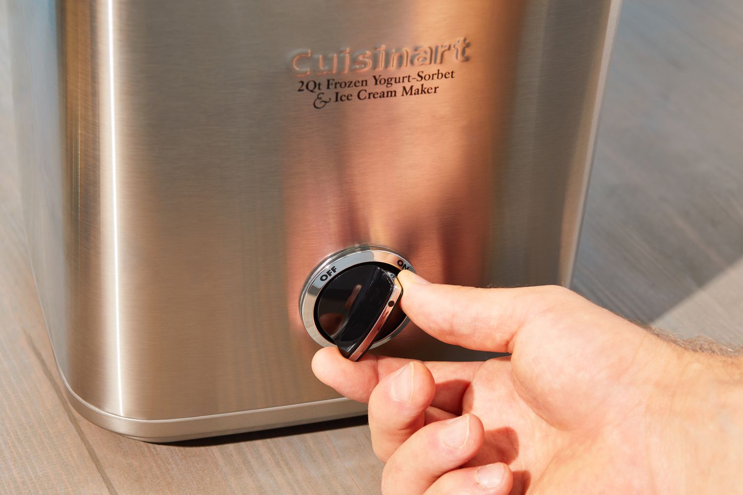 a closeup look at a hand turning on an ice cream maker