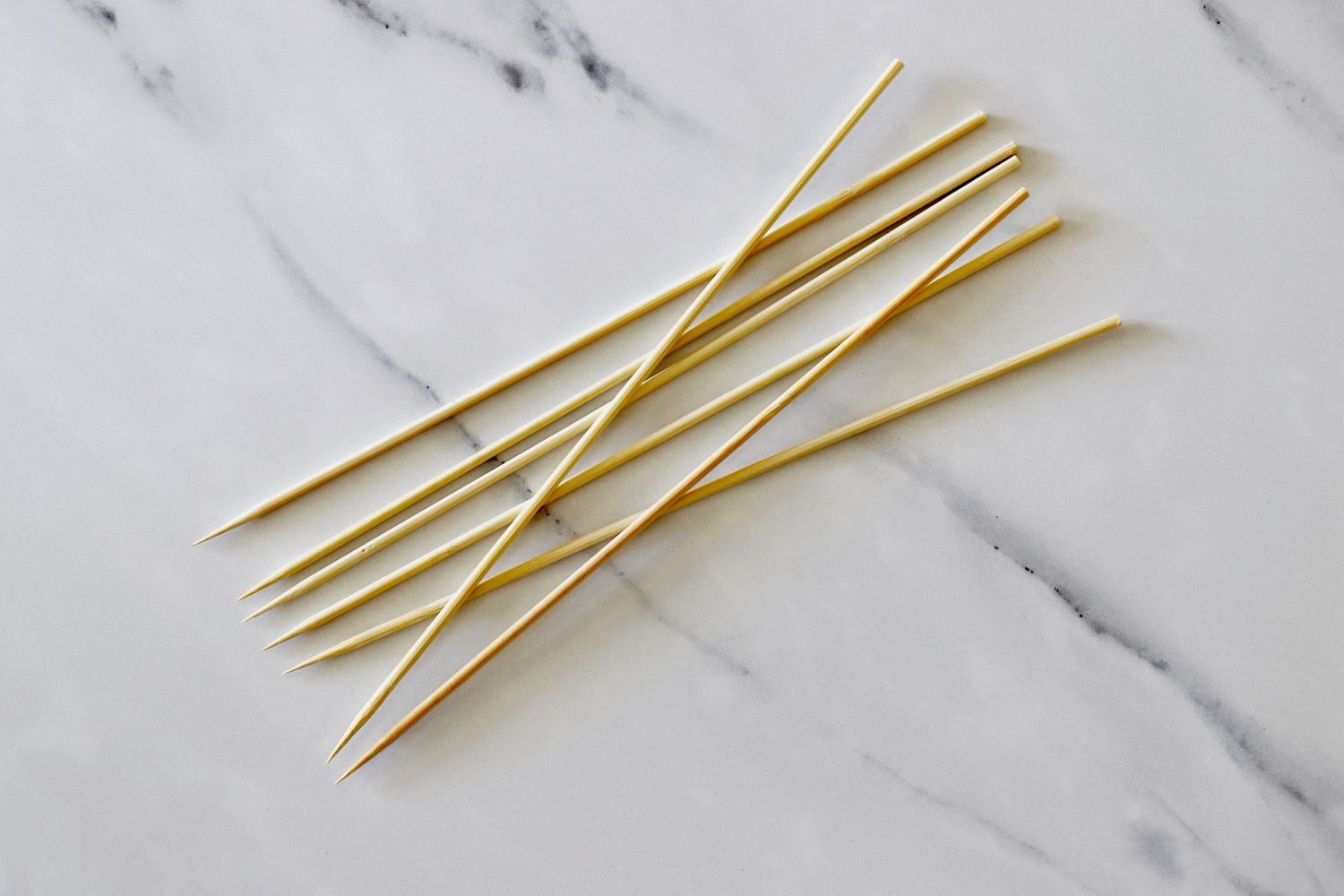 a handful of bamboo skewers on a marble surface