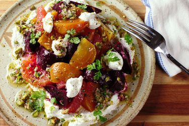 An overhead view of a colorful plate of beet and citrus salad with a pistachio dressing.