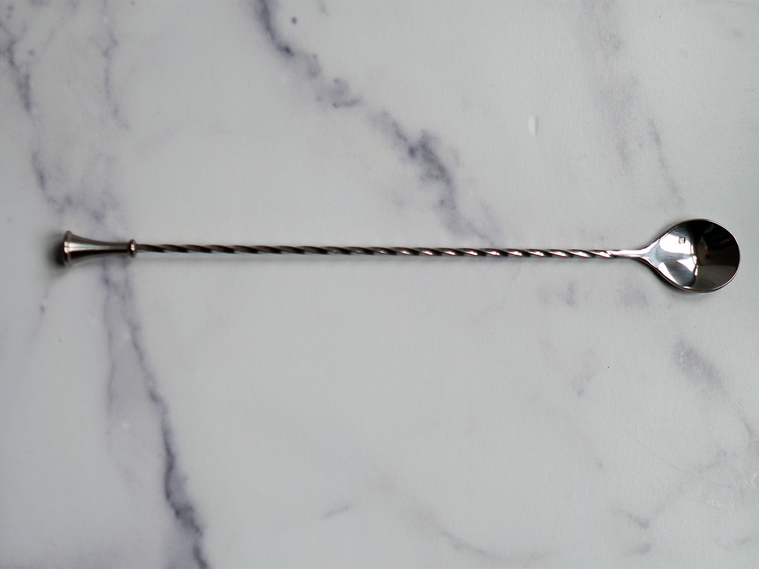 a stainless steel bar spoon on a marble surface