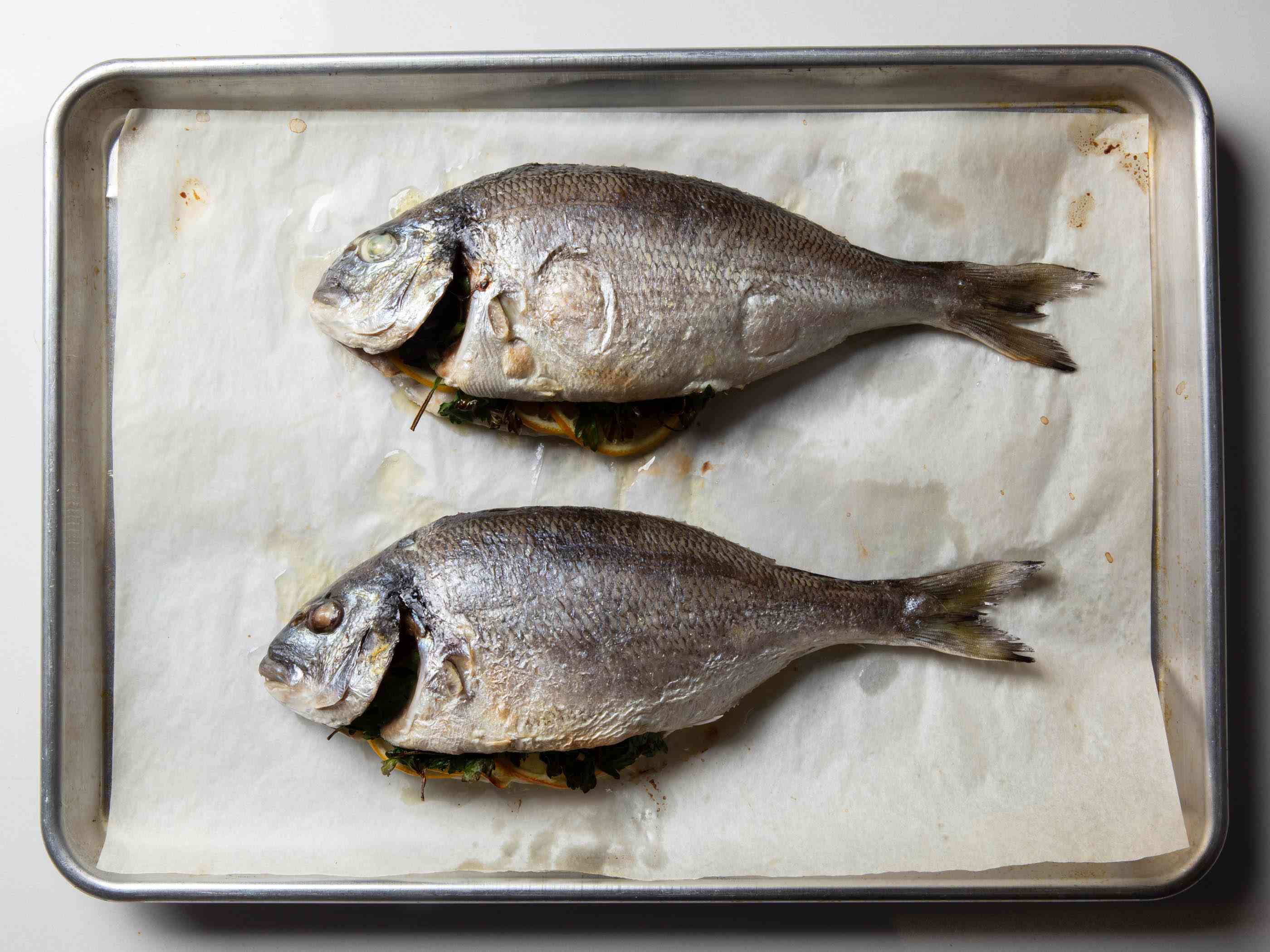 两条烤熟的整鱼放在烤盘上，鱼皮呈浅褐色。