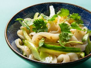 Bowl of cold sesame noodles topped with cucumber, celery, and cilantro