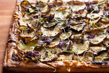 Closeup of an eggplant tart with goat cheese, honey, and nigella seeds.