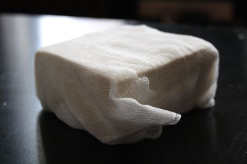 A block of tofu wrapped in cheese cloth.