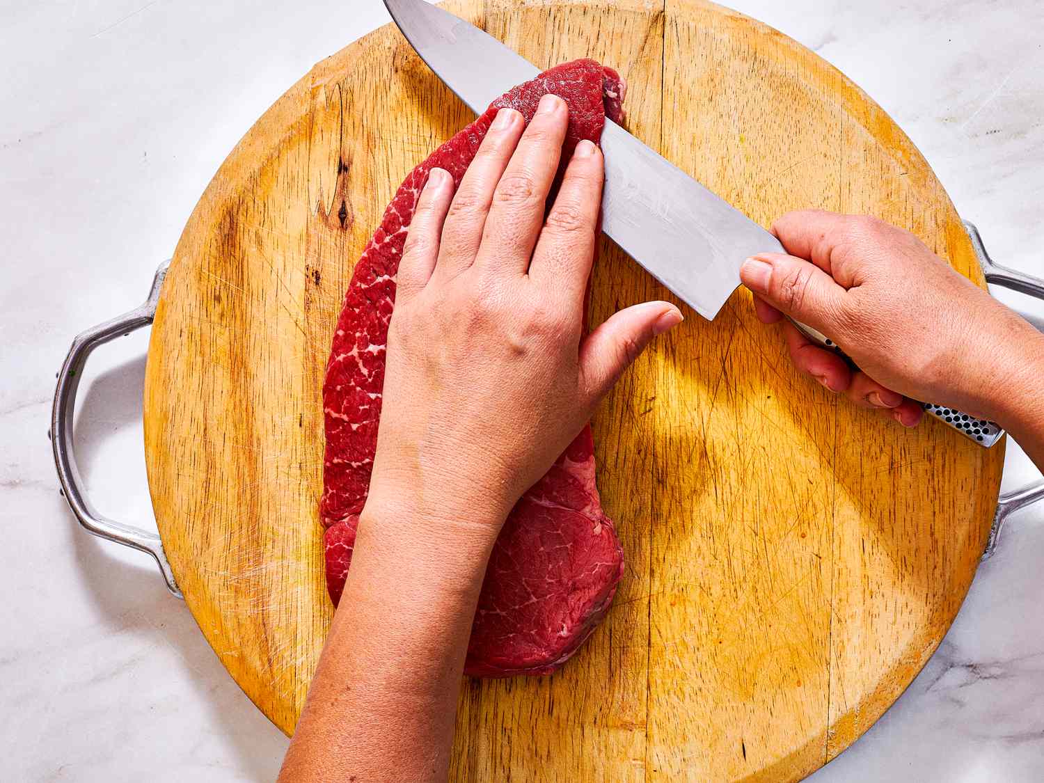 Overhead view of slicing top round into thin slices