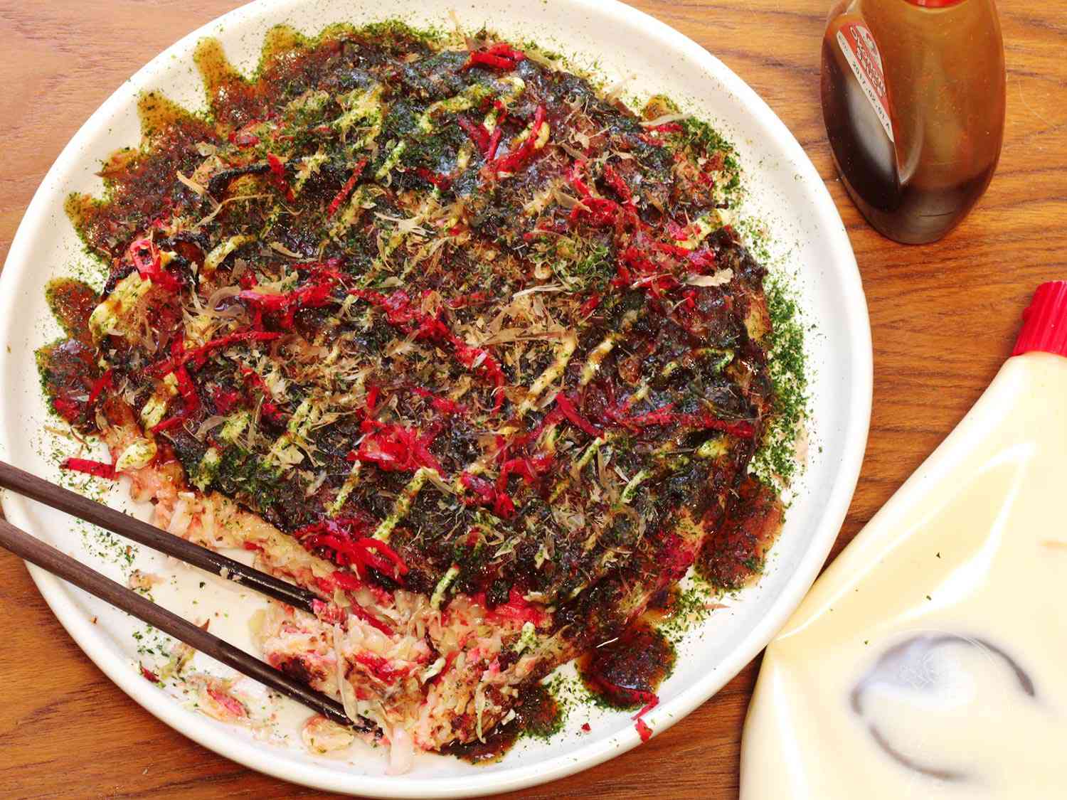 A pair of chopsticks on a plate of okonomiyaki