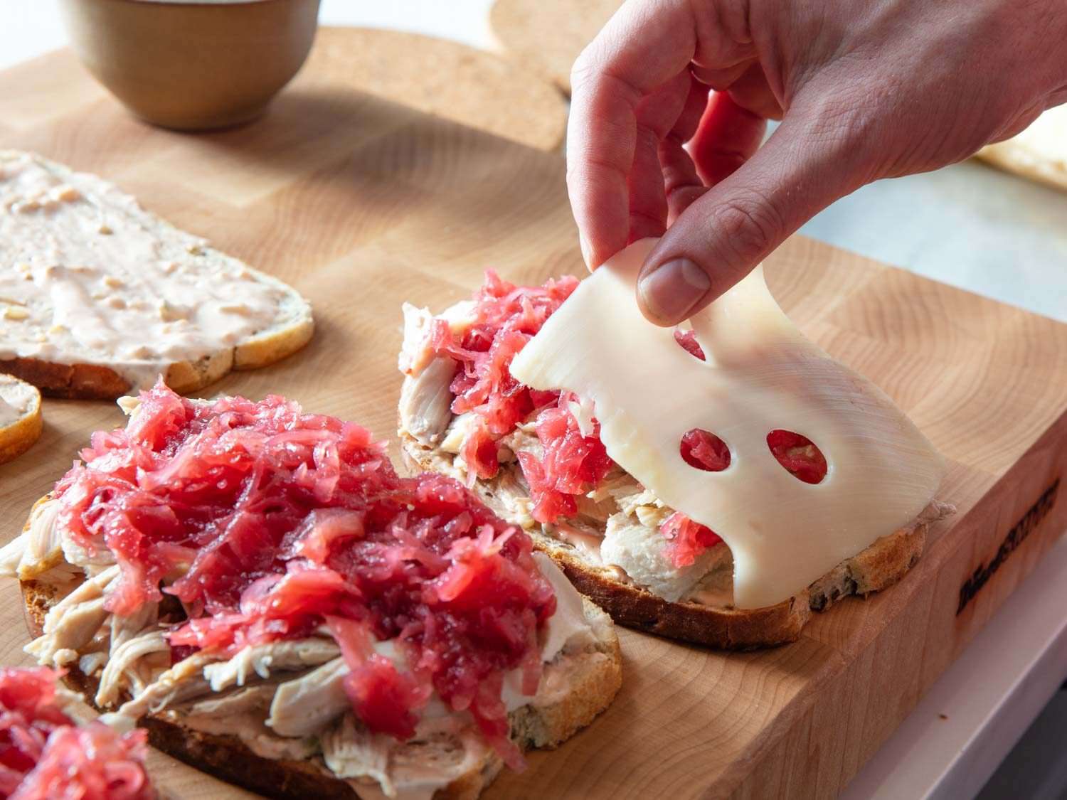 在蔓越莓酸菜上浇上瑞士奶酪，同时做鲁本三明治。