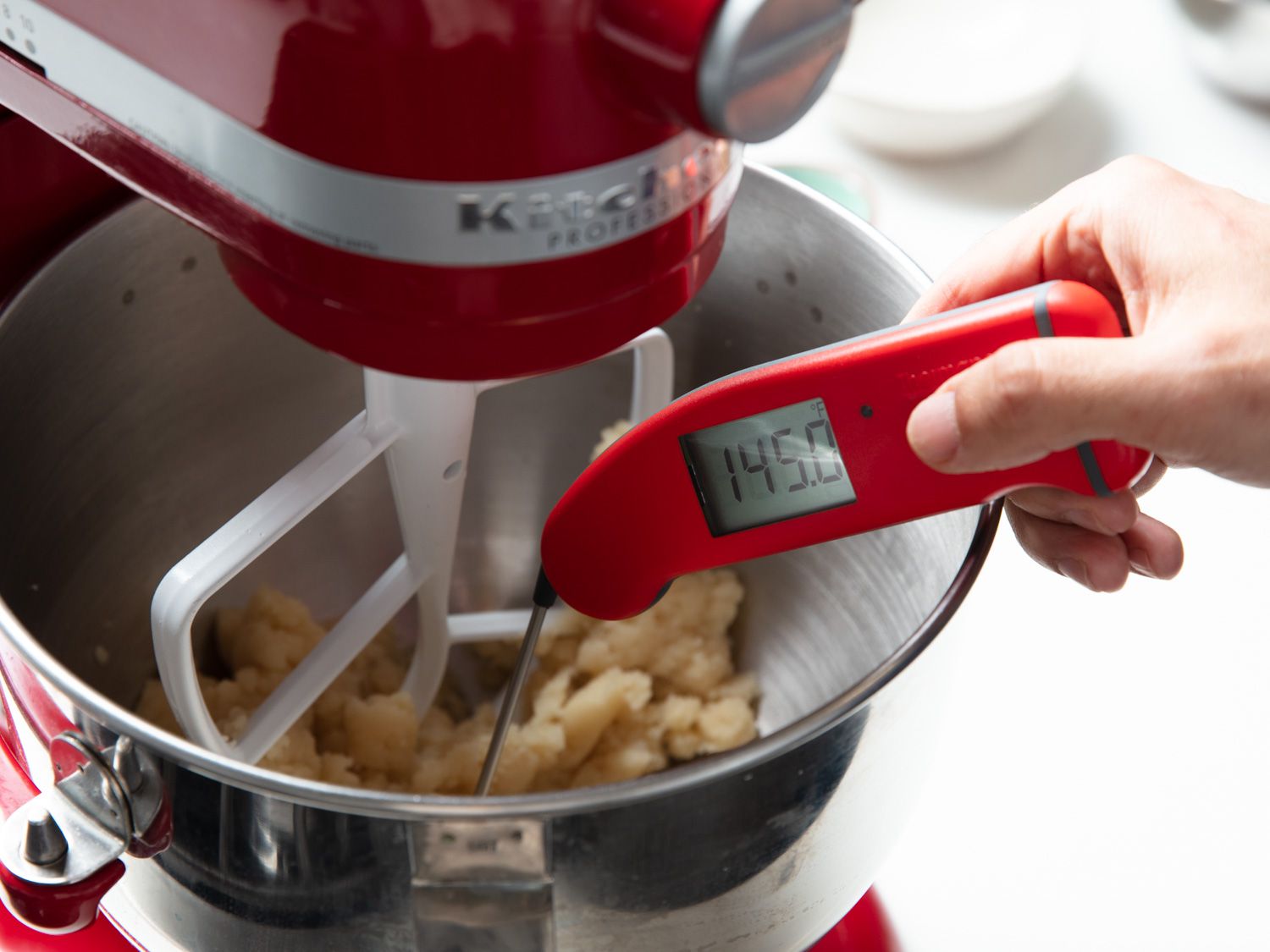 The paste is in the bowl of a stand mixer and registering 145 degree Fahrenheit (63 degrees C) on a thermometer.