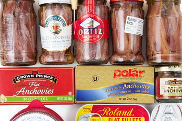 An assortment of cans and jars of anchovies.