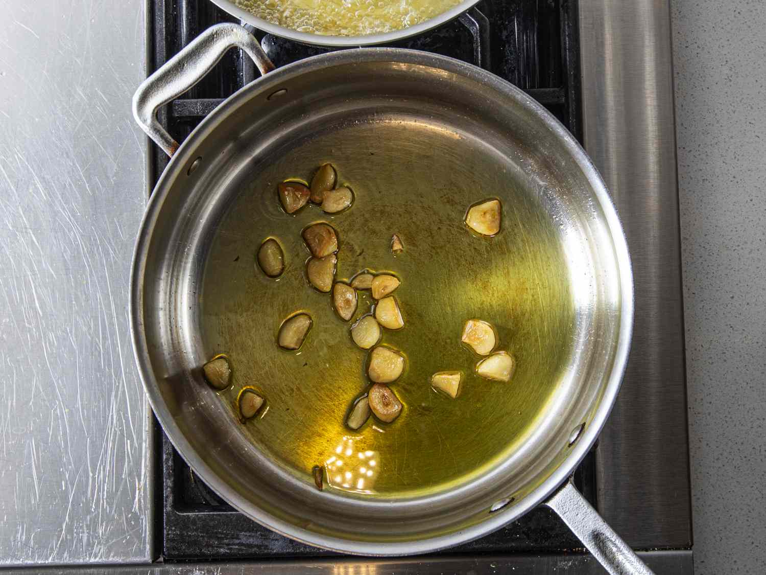 整瓣或接近整瓣的大蒜在平底锅里用橄榄油慢慢烹饪