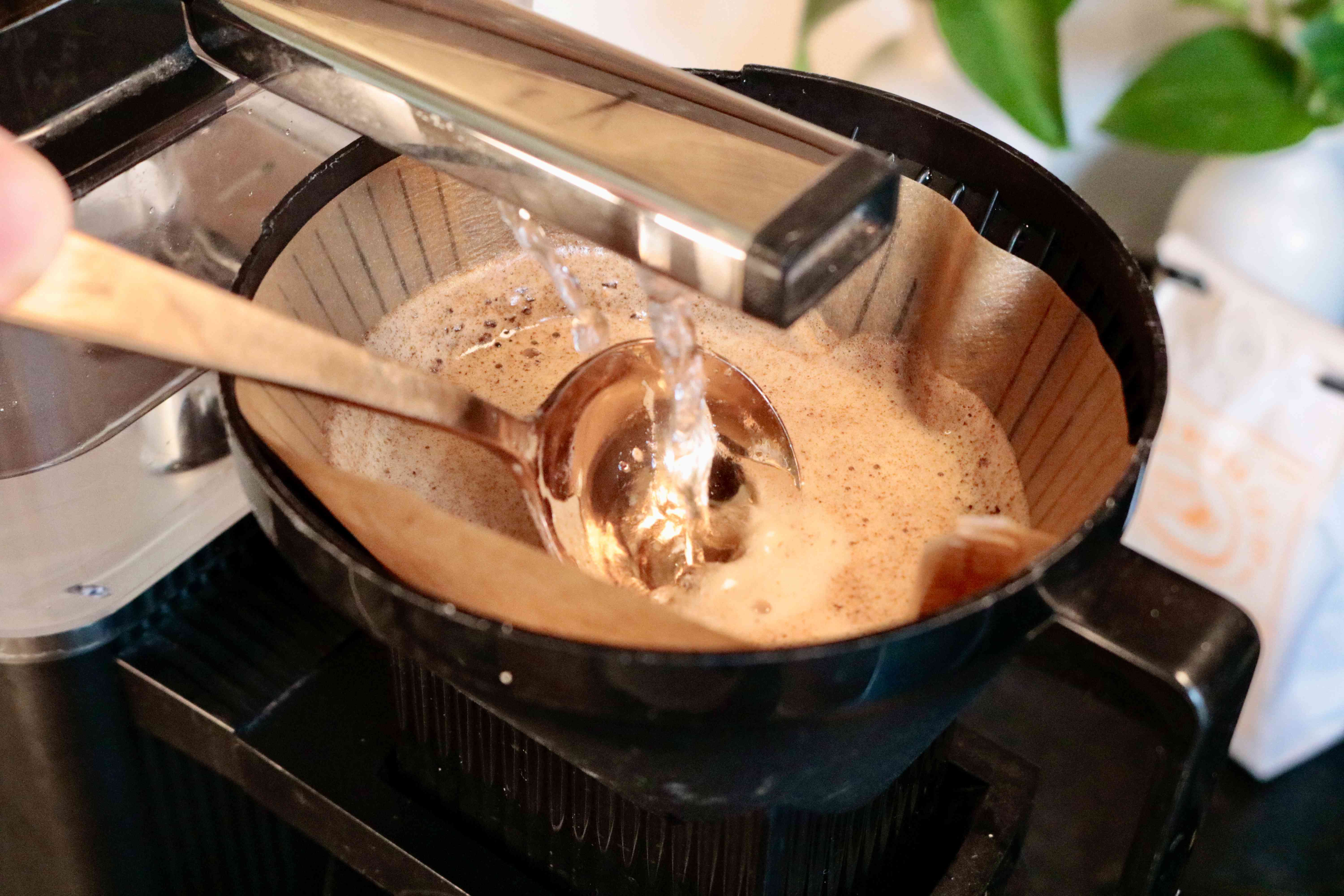 A spoon stirring coffee grounds as they brew