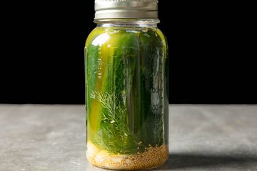 A jar of Milwaukee dill refrigerator pickles with garlic at the bottom.