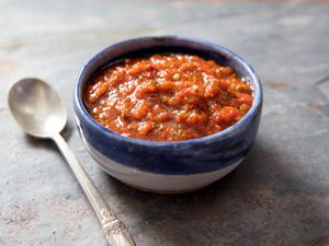 A bowl of fresh chile harissa with a spoon on the side