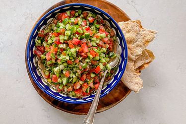 Overhead shot of Salata falahiyeh in a patterned blue bowl with crisp pita