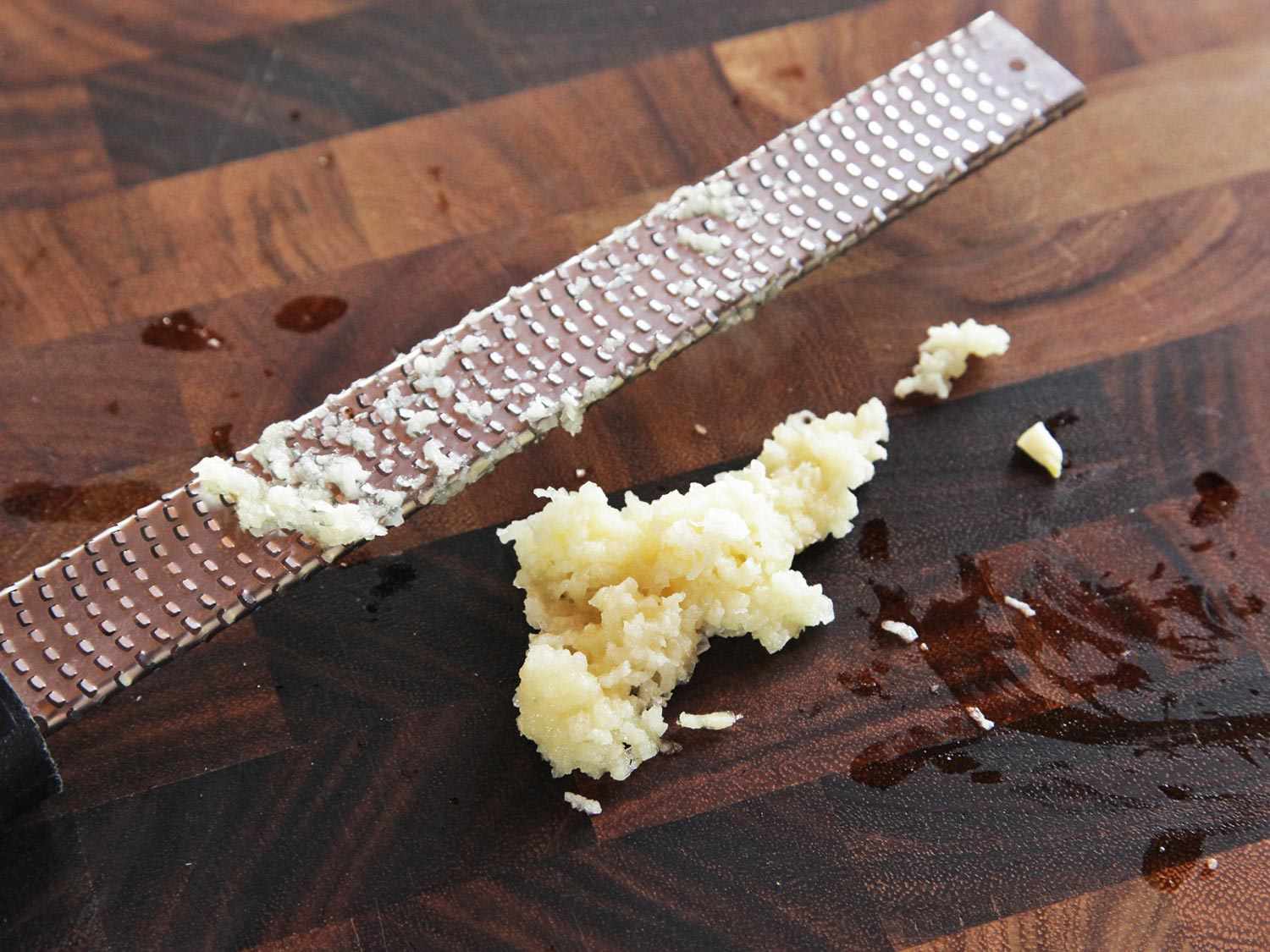 用微型刨刀在砧板上磨碎大蒜的特写。