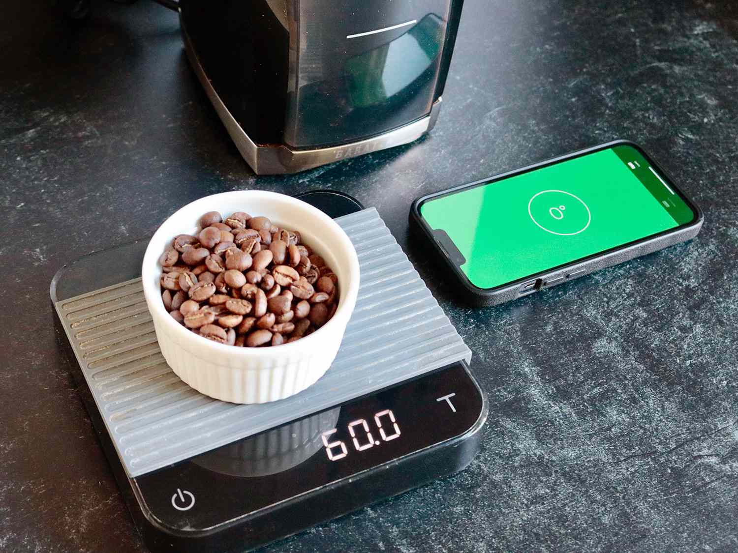 一个有水平应用程序的手机显示柜台的水平，旁边的秤上有咖啡的重量