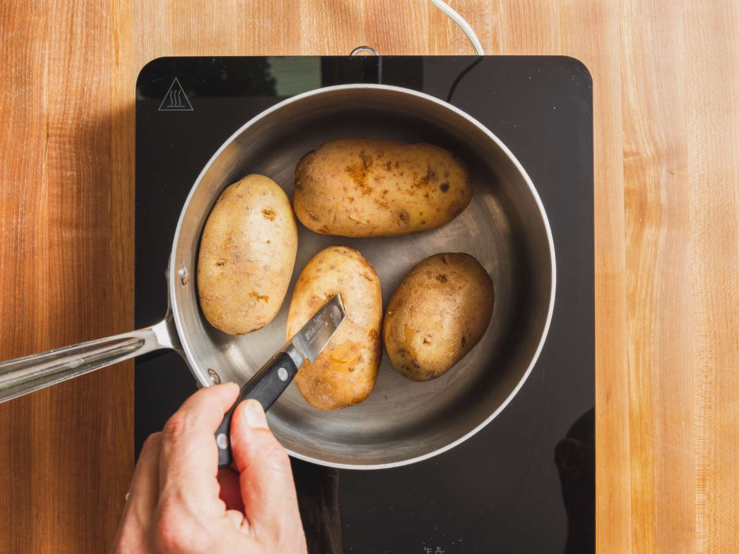 在平底锅中煮熟的土豆，用锋利的削皮刀检查是否熟透