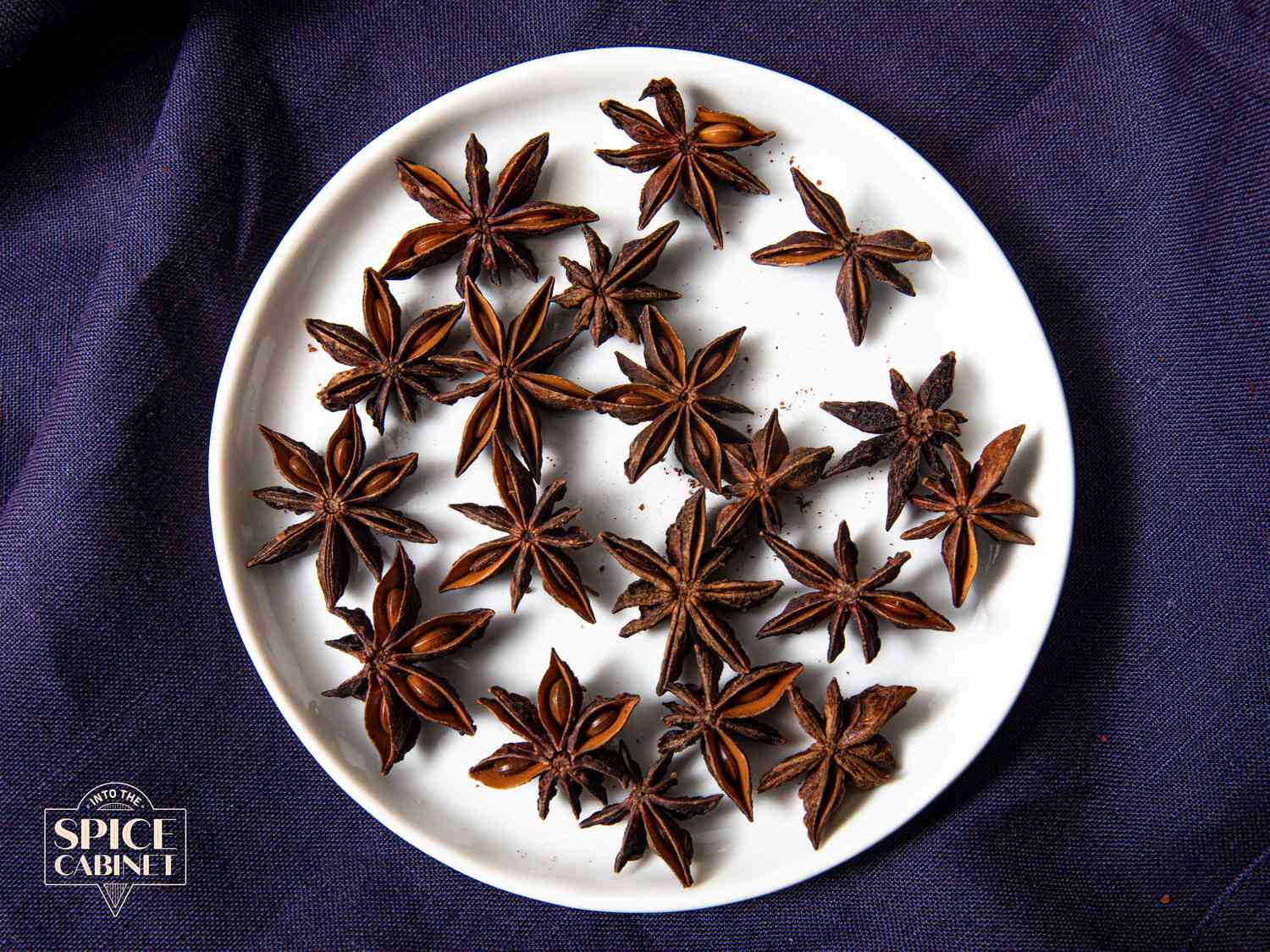 Overhead view of star anise on a plate on a purple background