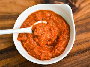 A small white bowl of ajvar, Serbian roasted red pepper sauce