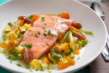 三文鱼à la nage与夏季蔬菜在一个白色浅碗。