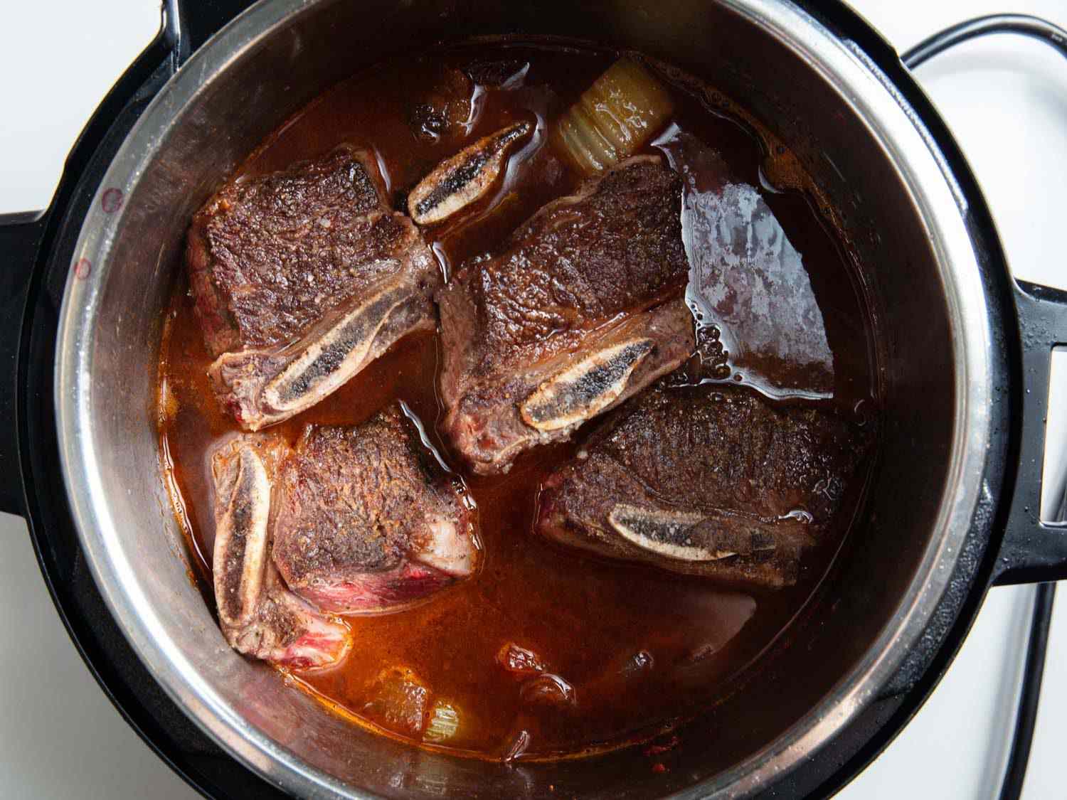 在高压锅中放入棕色的牛短排骨，在炖之前加入红酒和香料
