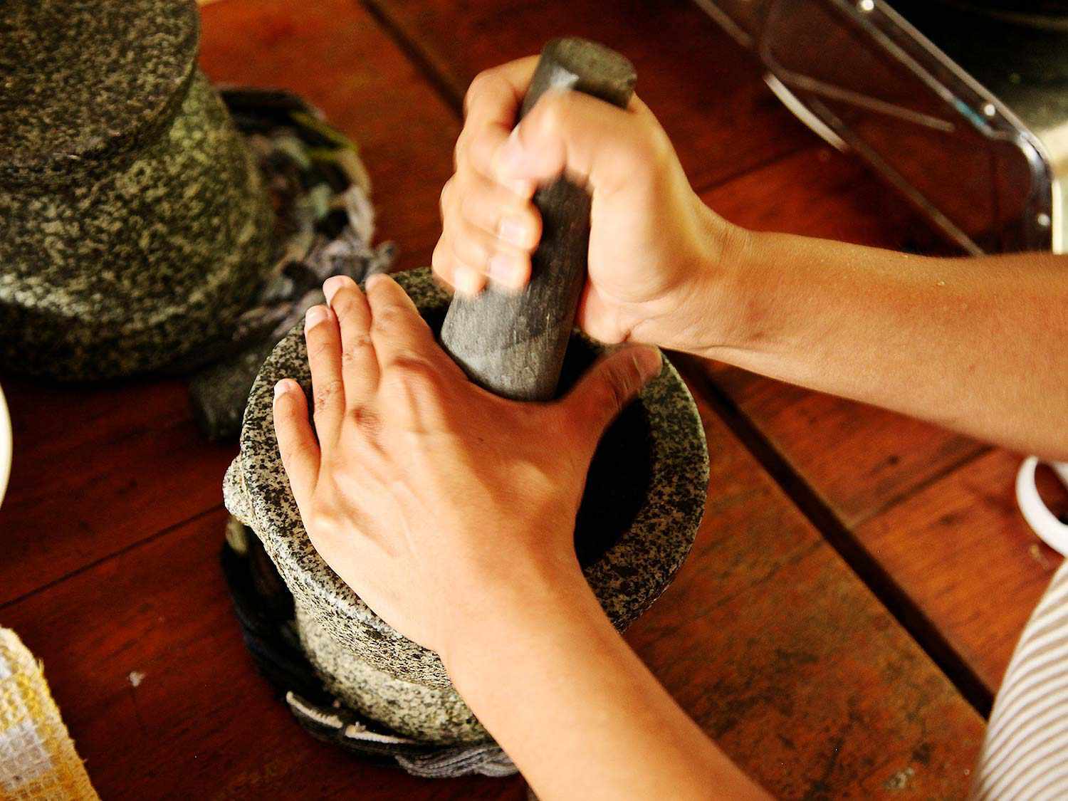用手在花岗岩研钵和研杵里捣咖喱酱。