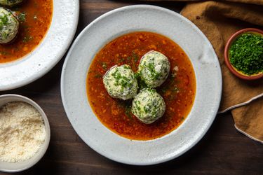 gnudi in a bowl with chives and parmesan cheese on the side