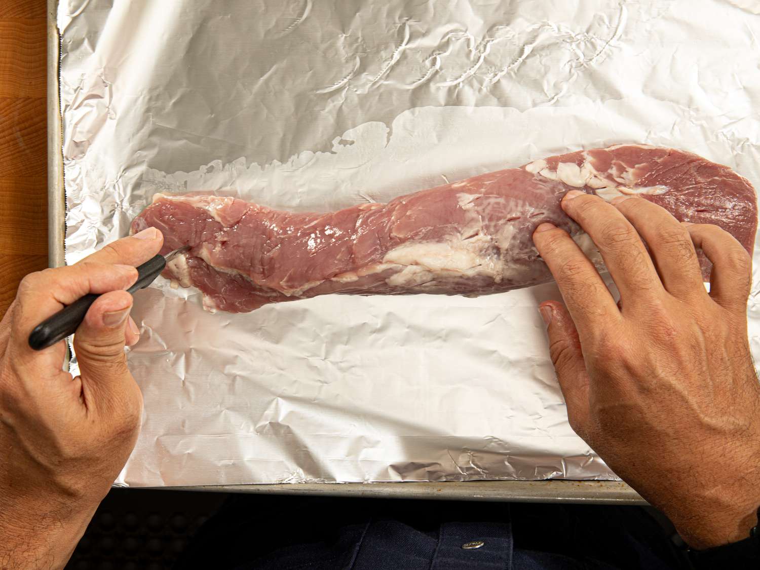 Overhead view of poking pork tenderloin with a knife