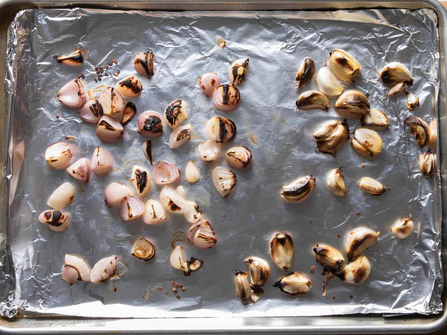 把大葱和没去皮的蒜瓣放在衬箔的烤盘上，烤到烧焦。