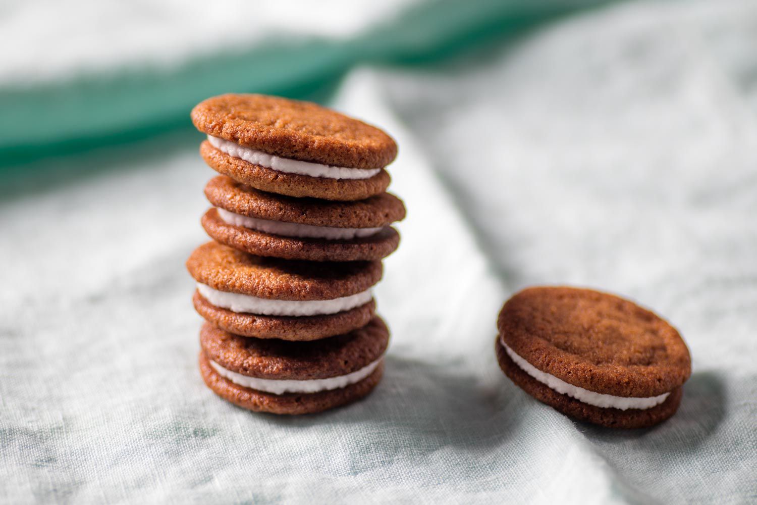 A tall stack of the lemon-ginger sandwich cookies, with a stray cookie off to one side.