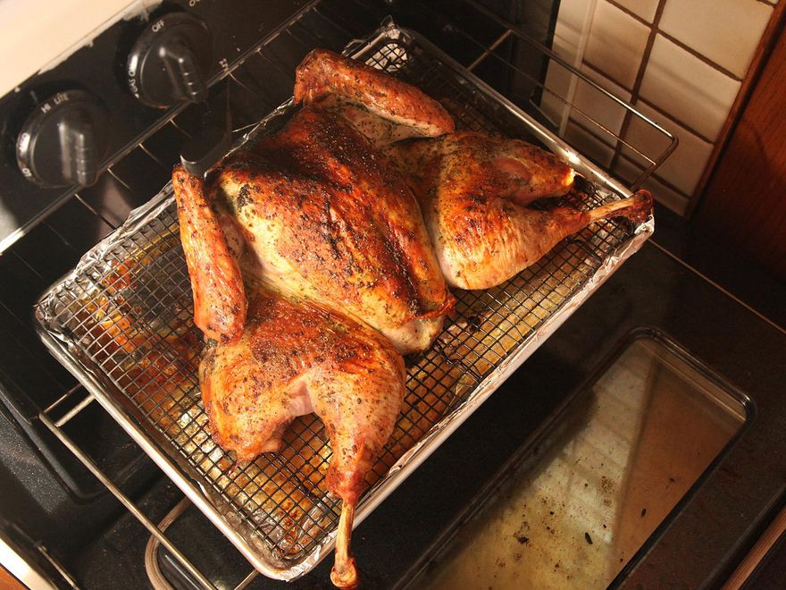 香草擦脆皮蝴蝶烤火鸡放在烤炉的架子上。