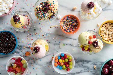 小盘各式各样的冰淇淋，上面撒有糖屑、糖果、坚果和水果