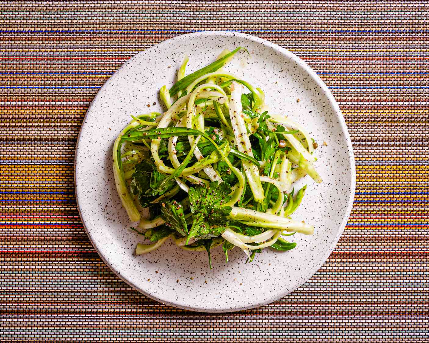 Overhead view of puntarelle salad on a colorful stripped background