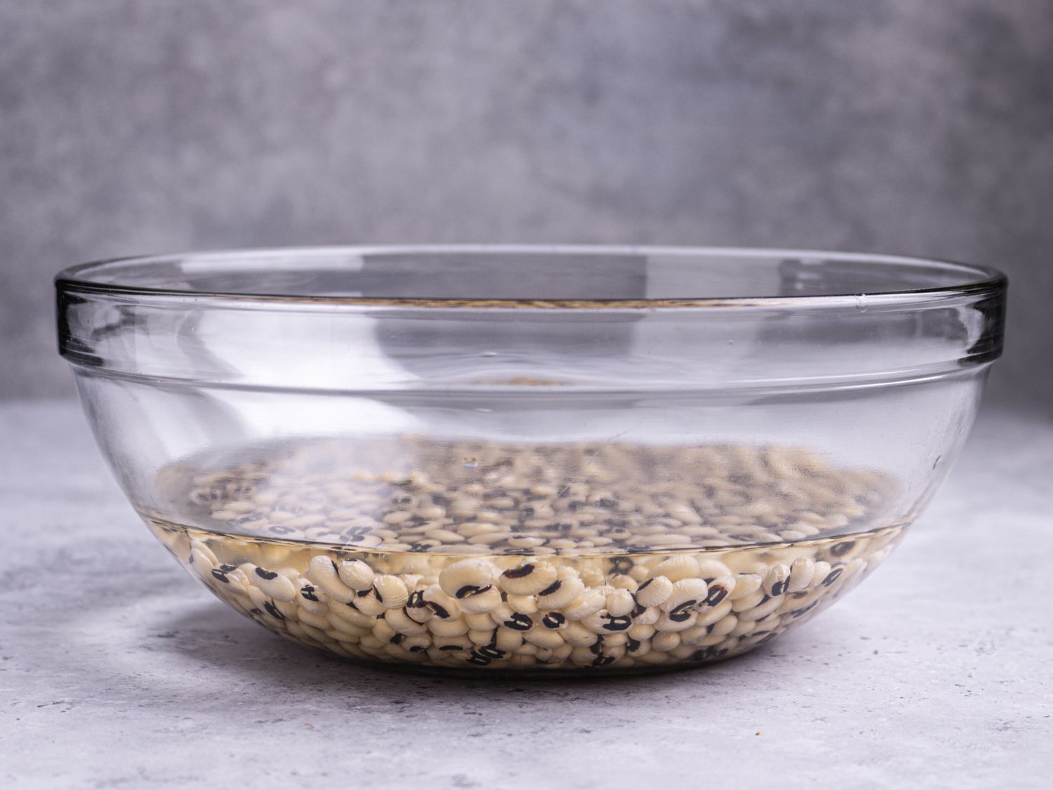 Peas soaking at the bottom of a glass bowl filled with water