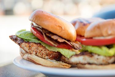 Closeup of grilled blackened-fish sandwiches served outdoors on a white platter.