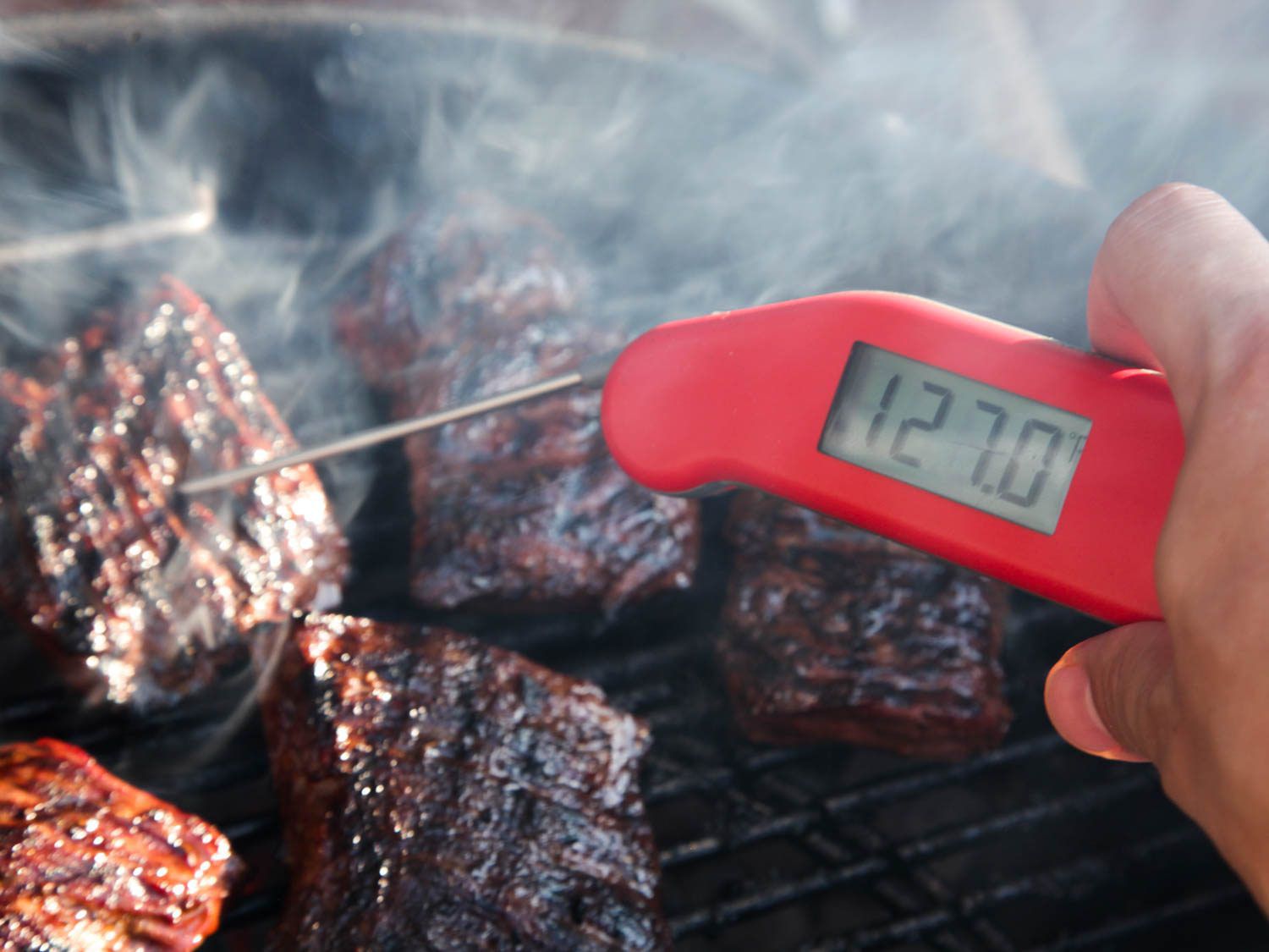 在烤架上烤着的几块牛排中，插入一个即时读数的温度计。