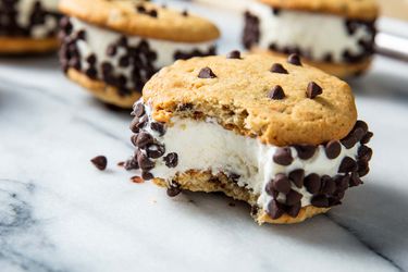 Closeup of a half-devoured, chocolate chip-studded chipwich. Other chipwiches are visible in the blurred background.