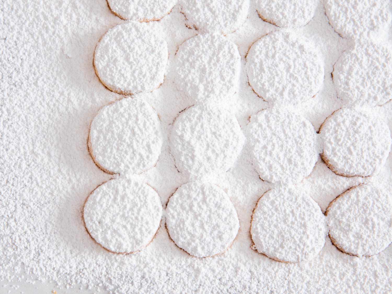 Rows of lemon meltaway cookies covered in a heavy layer of powdered sugar