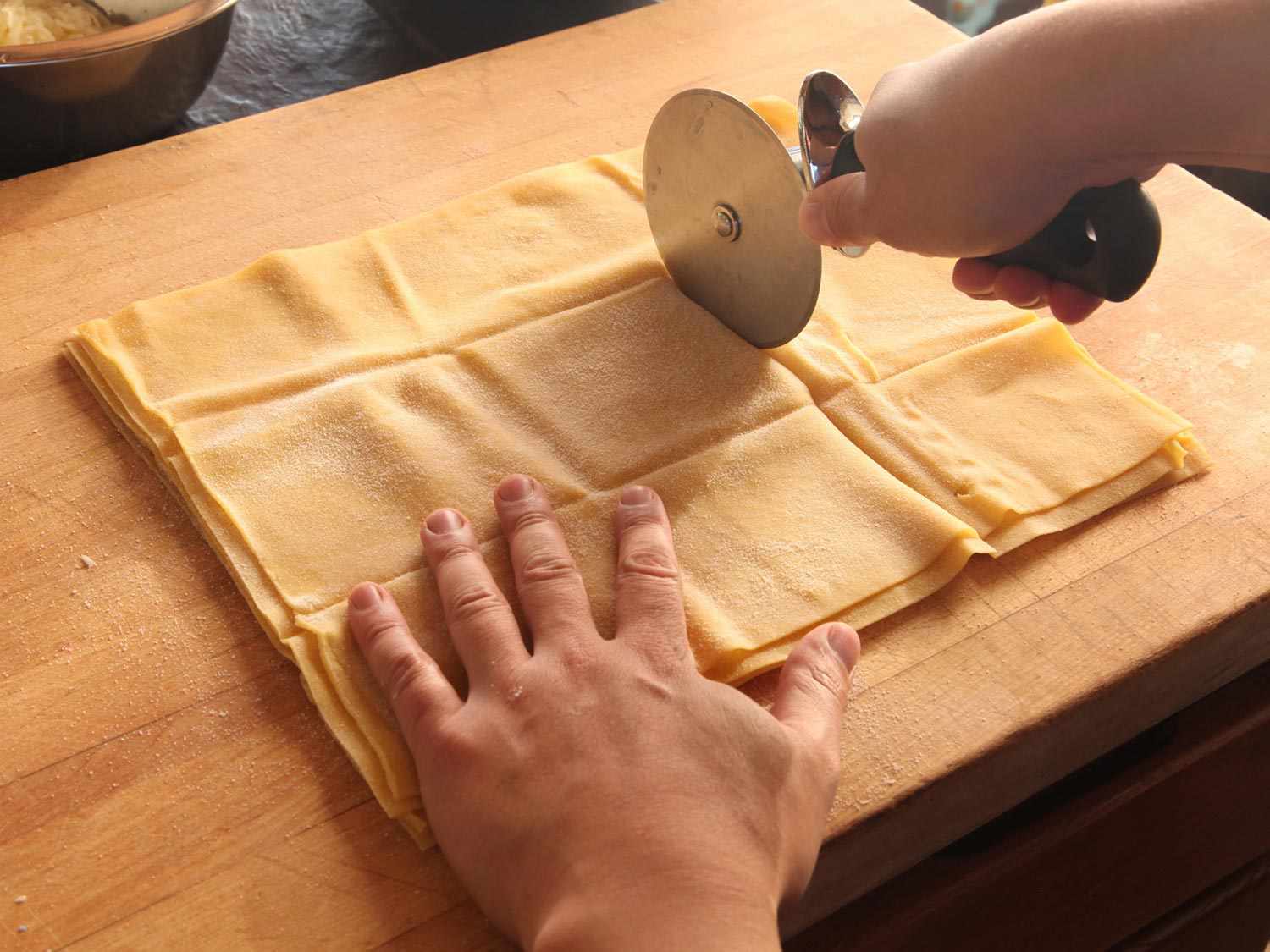 Fresh pasta sheets cut down to size with a pizza wheel