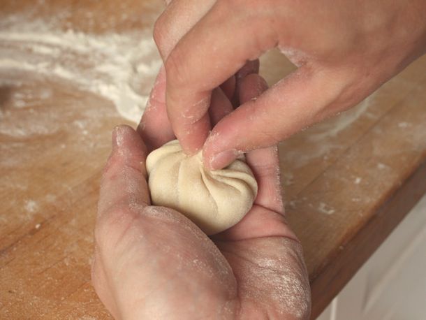 The crimped dumpling is pinched at the top to seal the filling inside.