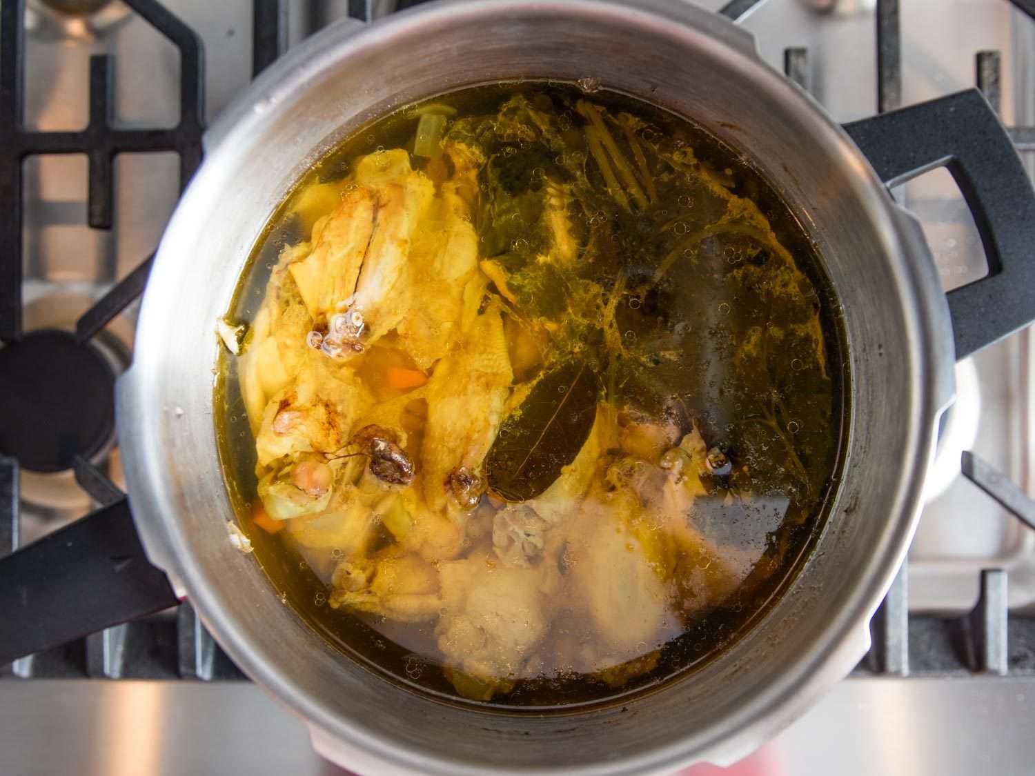 Overhead view of ingredients for chicken stock in a stovetop pressure cooker.