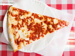 A slice of New York pizza on a paper plate.