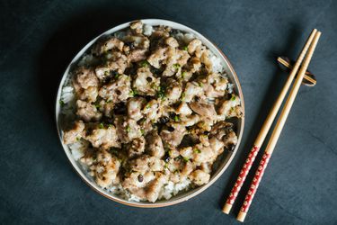 Overhead view of Steamed Pork Ribs on a plate of rice placed next to a pair of chopsticks.