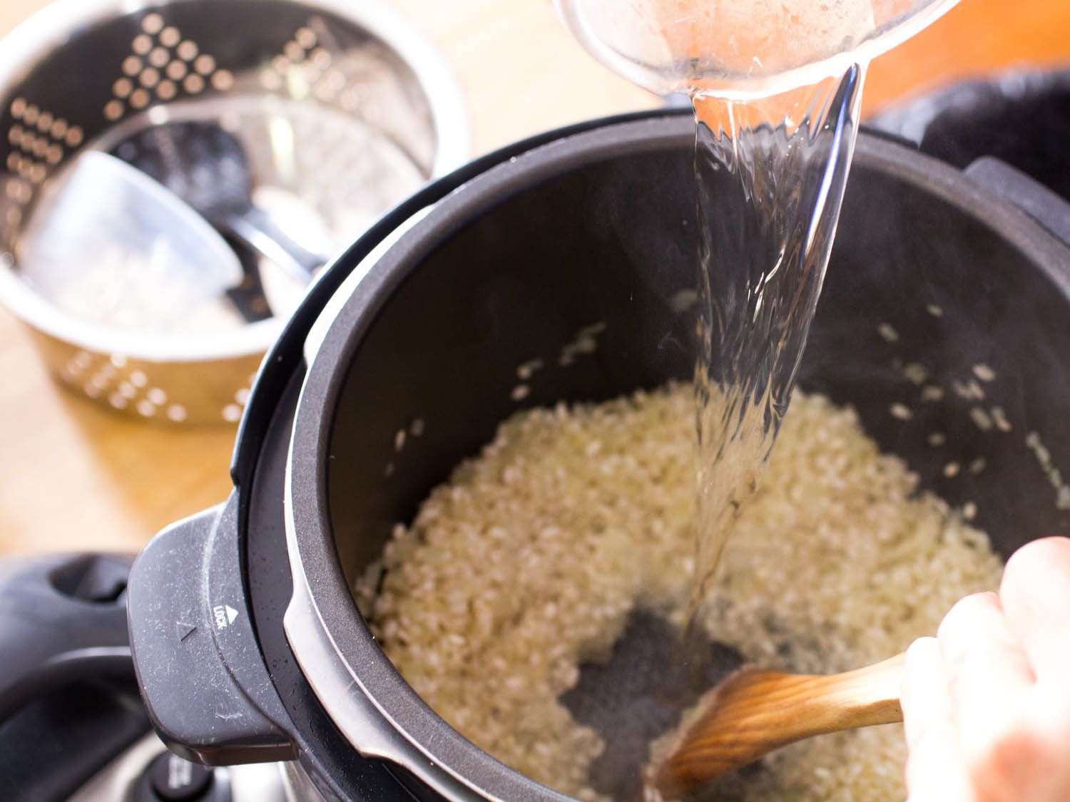 Chicken stock being poured into pressure cooker for risotto