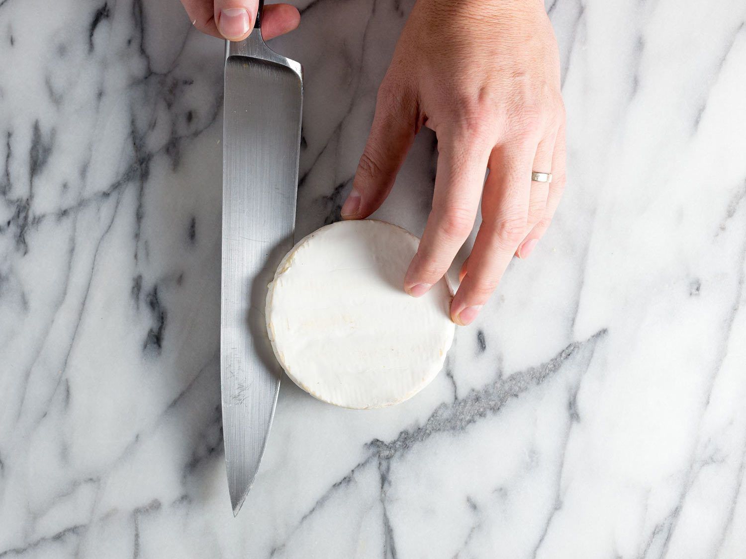 Slicing a round of brie in half.