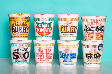 8 varieties of Cup Noodle instant ramen are displayed against a light blue background.