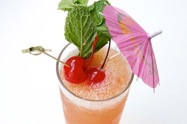 Zombie punch cocktail with cherries, mint, and an umbrella